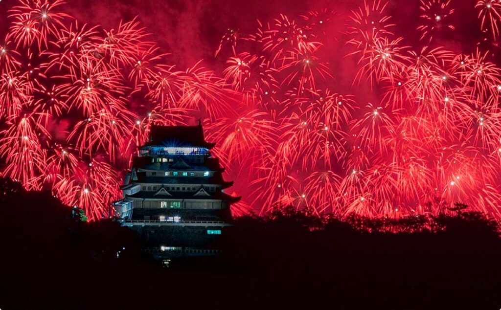 热海城堡在鲜红焰火的映衬下巍然屹立。